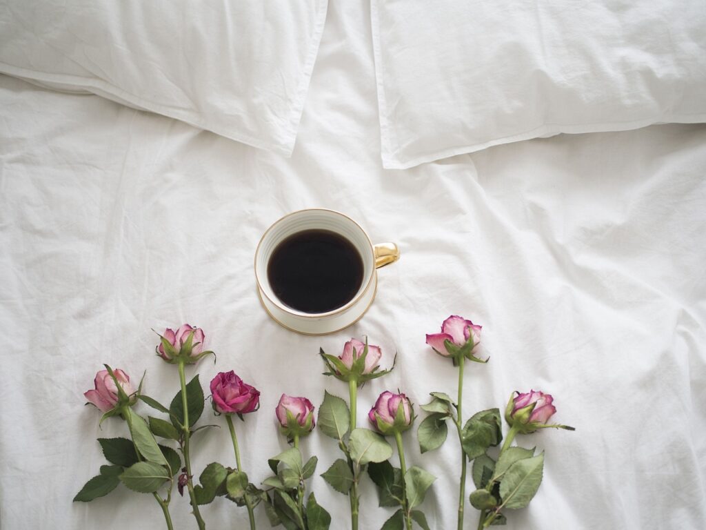 ベッドの上にコーヒーとお花が飾られている写真
